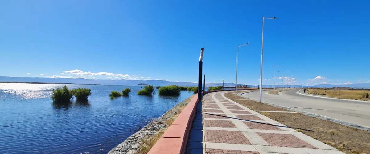 Costanera del Lago Argentino en El Calafate al atardecer con el cielo anaranjado reflejándose en el agua