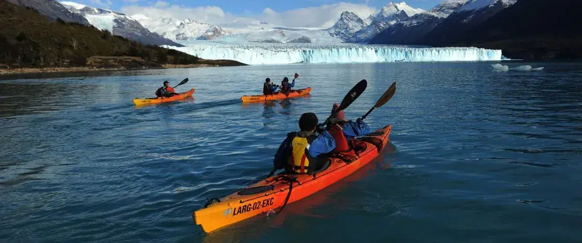 Kayakistas remando entre témpanos de hielo azul frente a la pared del Glaciar Perito Moreno